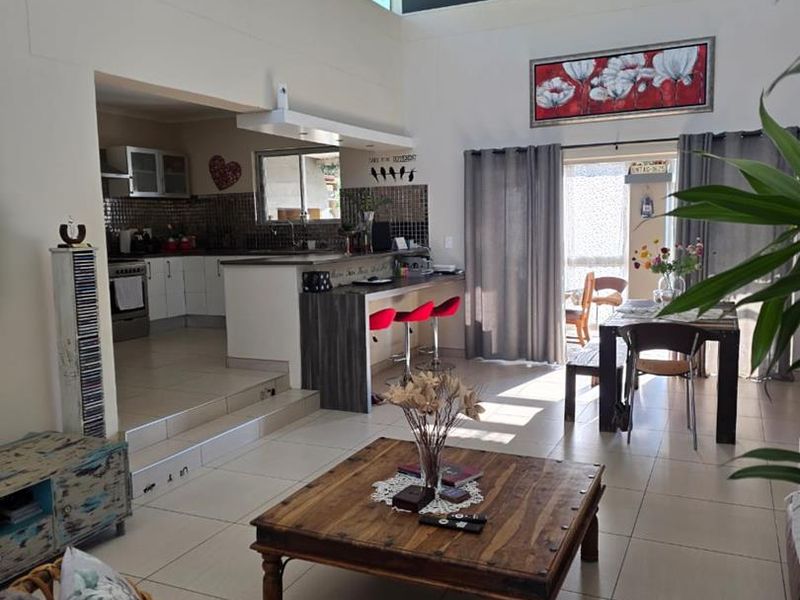 Spacious open-plan living area featuring a vaulted ceiling, clerestory windows, tiled floors, and a breakfast bar connecting to the kitchen.