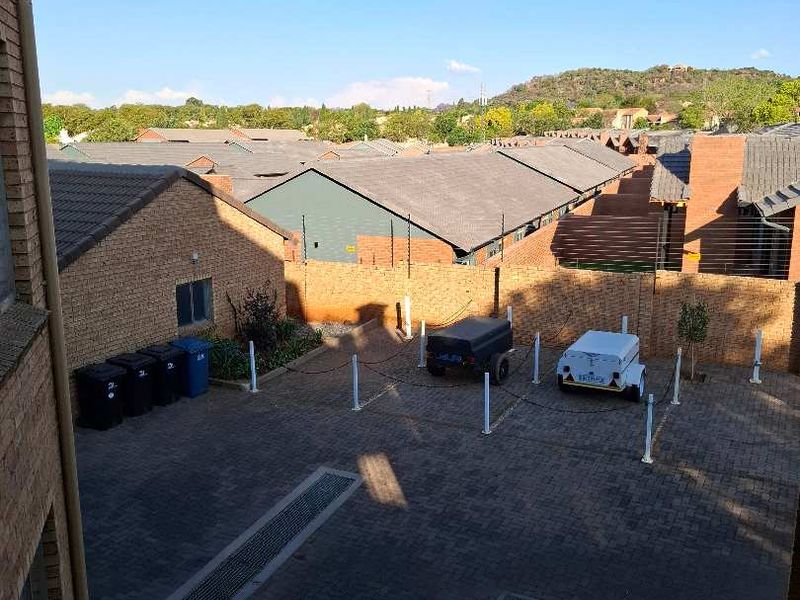Elevated view of the rear paved courtyard area, featuring brick boundary walls with integrated electric fencing and drainage infrastructure.