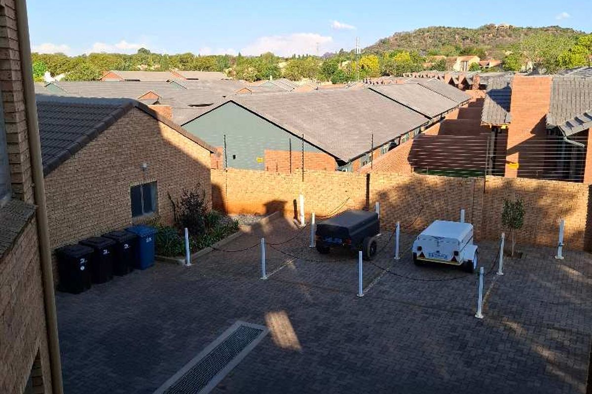 Elevated view of the rear paved courtyard area, featuring brick boundary walls with integrated electric fencing and drainage infrastructure.