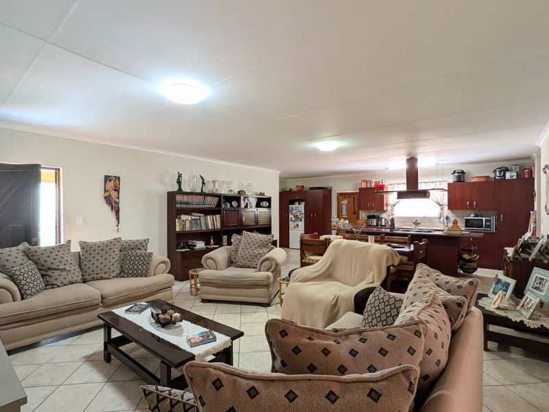 Spacious open-plan living area featuring a functional kitchen with built-in cabinetry, a central island, and tiled flooring throughout the combined lounge and dining space.