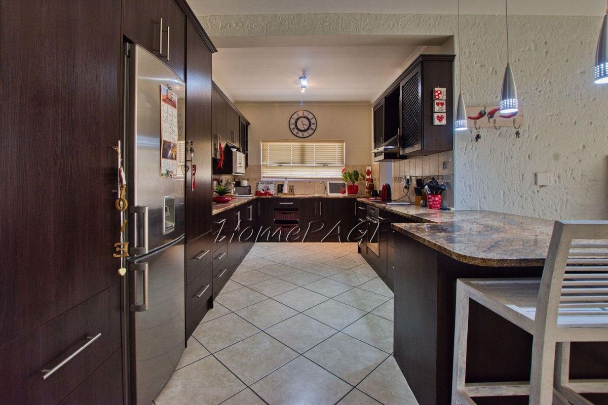 A well-appointed kitchen featuring dark cabinetry, granite countertops, tiled flooring, and a breakfast bar, offering a functional and modern cooking space.