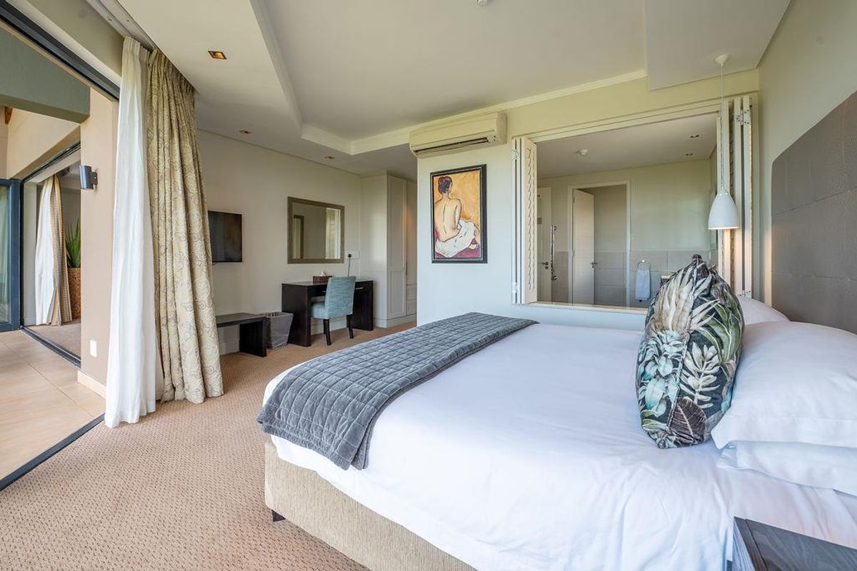 Spacious bedroom featuring carpeted flooring, built-in cabinetry, wall-mounted air conditioning, and large sliding doors opening onto a private balcony.