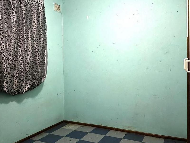 An empty bedroom featuring worn checkered vinyl flooring and walls in need of cosmetic repair and repainting.