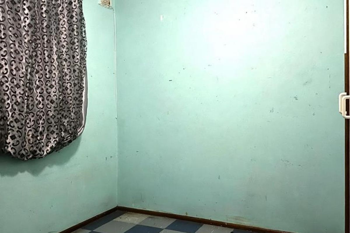 An empty bedroom featuring worn checkered vinyl flooring and walls in need of cosmetic repair and repainting.
