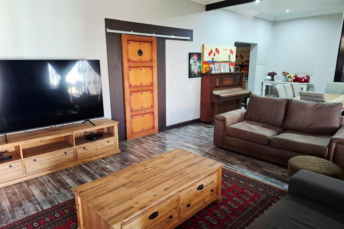 Spacious living room featuring a distinctive sliding barn door, exposed ceiling beam, recessed lighting, and durable laminate flooring.