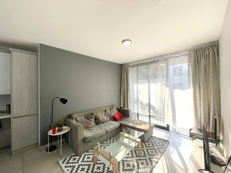 A bright living room featuring tiled flooring, built-in cabinetry, and a large sliding glass door that provides ample natural light.