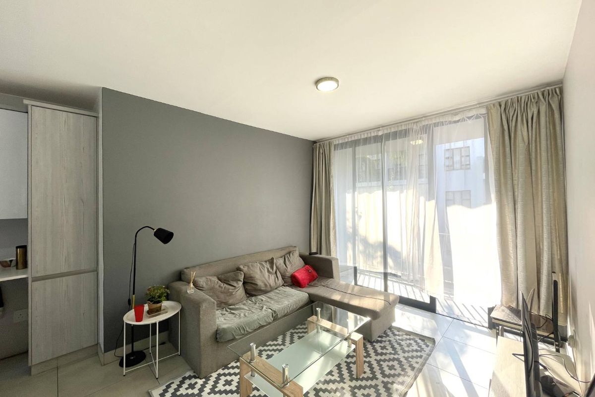 A bright living room featuring tiled flooring, built-in cabinetry, and a large sliding glass door that provides ample natural light.