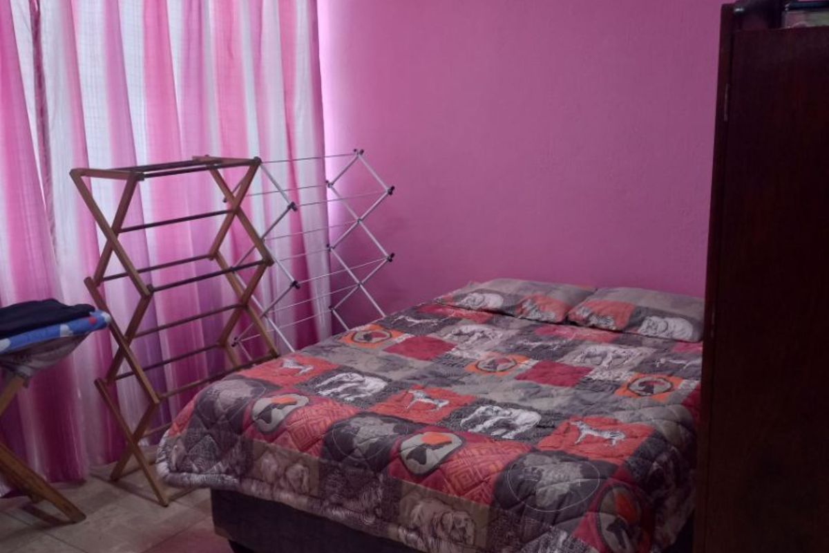 A bedroom featuring tiled flooring and pink painted walls, providing a functional space for rest.