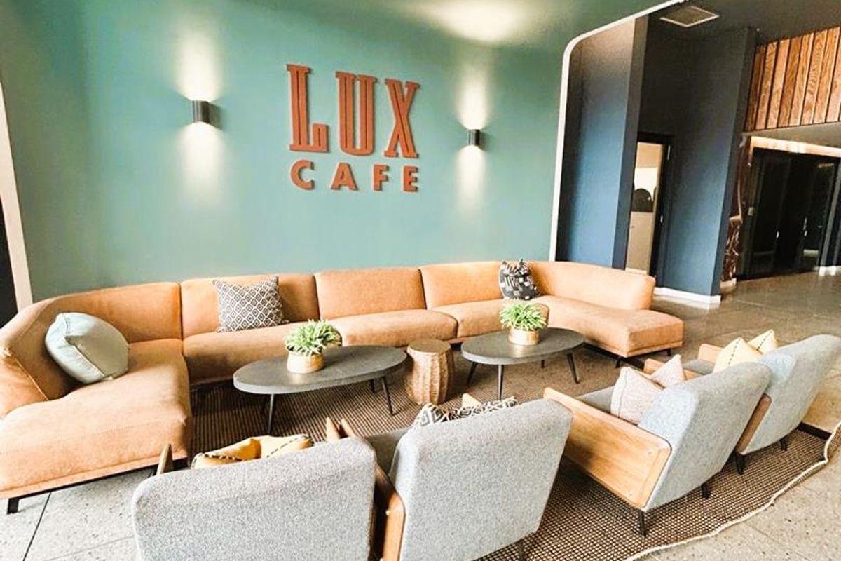 A modern lounge area featuring terrazzo flooring, recessed ceiling lighting, and a feature wall with integrated wall sconces.