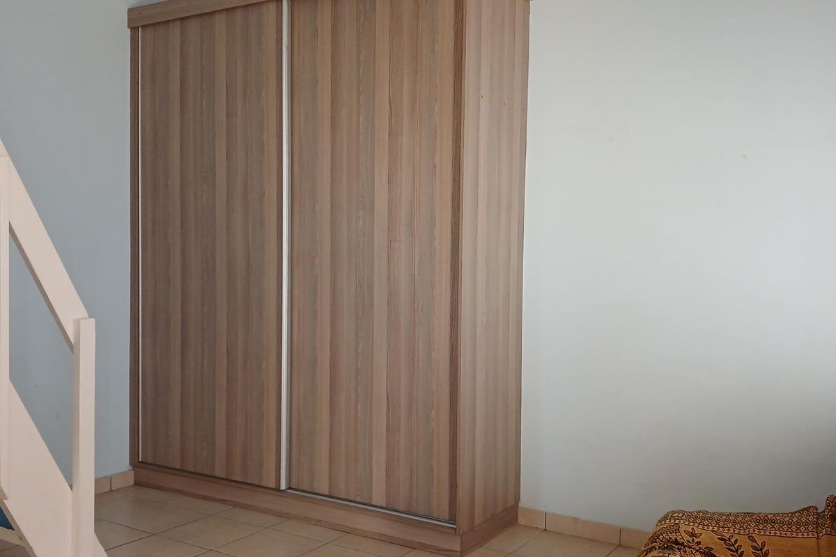 Bedroom featuring a built-in wood-finish sliding door wardrobe and an adjacent staircase.