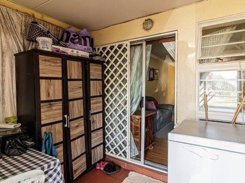 Enclosed patio area featuring tiled flooring, a sliding glass door with security gate, and external wall lighting, providing access to the interior living space.