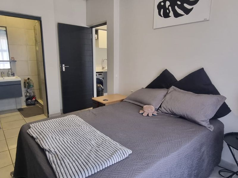 A well-maintained bedroom featuring tiled flooring, built-in cupboards, and direct access to an en-suite bathroom.