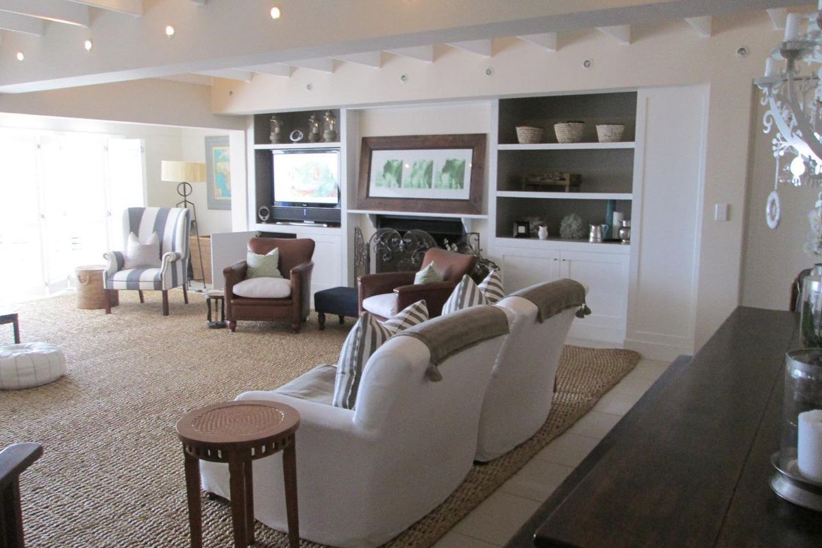 Spacious living room featuring a built-in fireplace with integrated shelving and cabinetry, exposed ceiling beams, and tiled flooring.