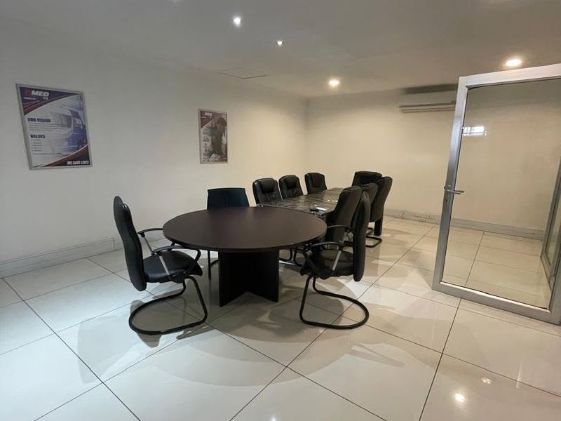 A modern office space featuring polished tiled flooring, recessed ceiling lighting, and an integrated air conditioning unit with an aluminium framed glass entrance.