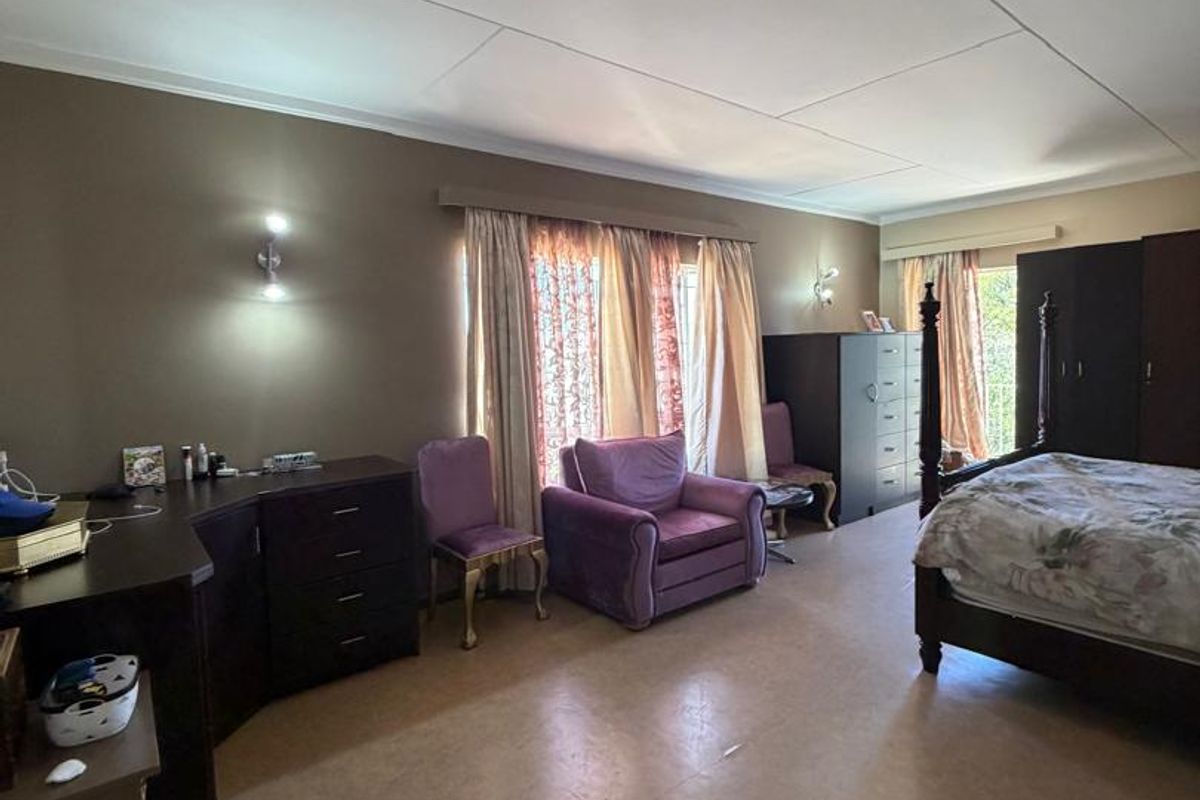 Spacious bedroom featuring neutral wall tones, tiled flooring, and dual window access with curtain rails, offering a comfortable and functional living space.