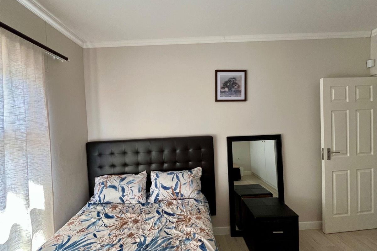 A well-maintained bedroom featuring neutral wall tones, crown molding, and light-colored flooring, providing a clean and comfortable living space.