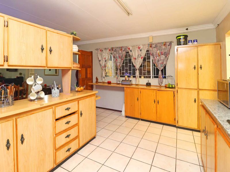 A functional kitchen featuring extensive laminate cabinetry, tiled flooring, and ample counter space, offering a practical layout with potential for modern updates.