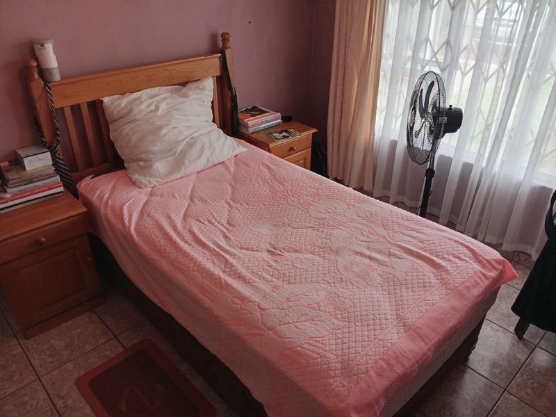 A bedroom featuring tiled flooring and a window fitted with a security gate, providing a functional and lived-in space.