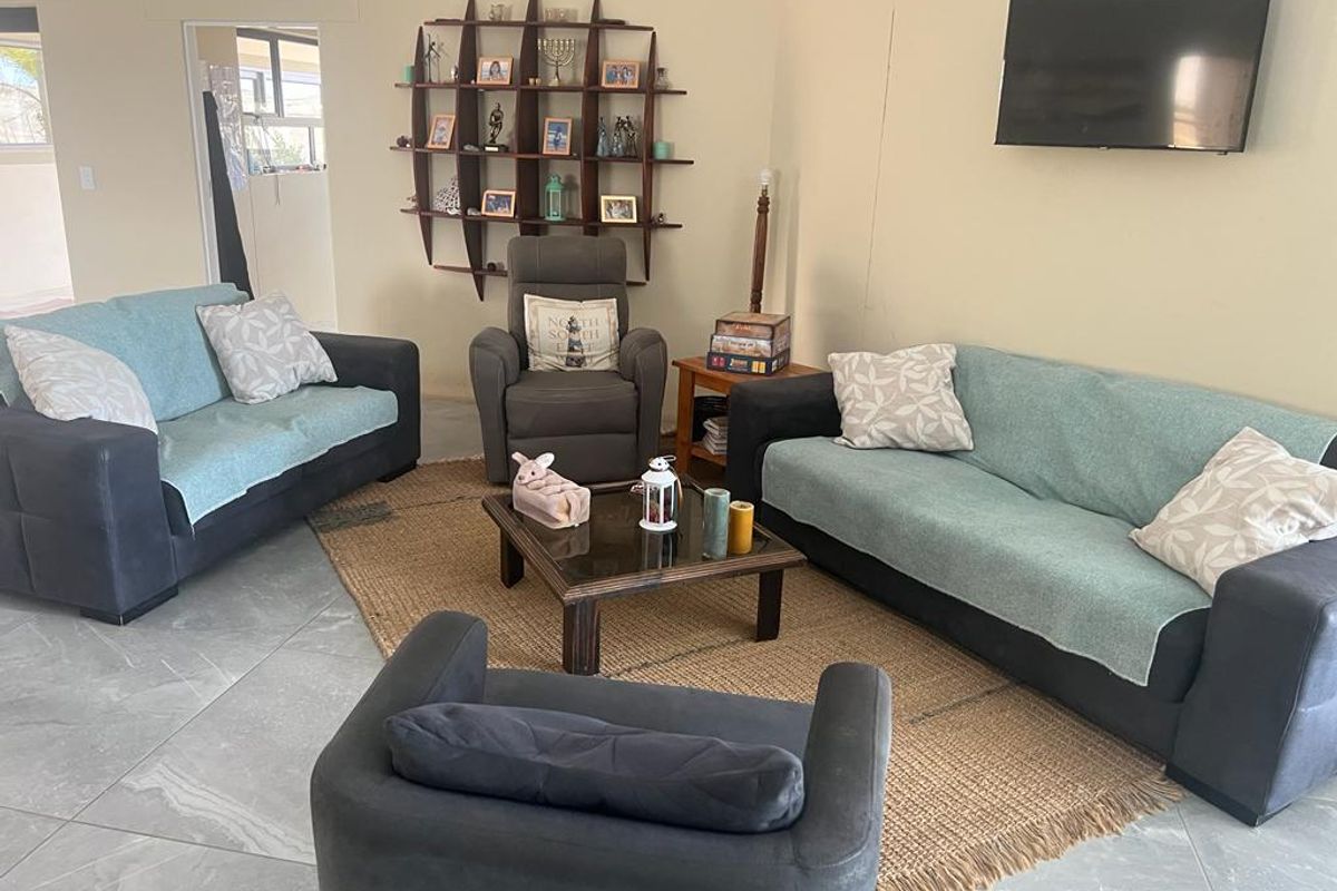 A comfortable living room featuring large format floor tiles and a neutral wall palette, providing a functional space for relaxation.