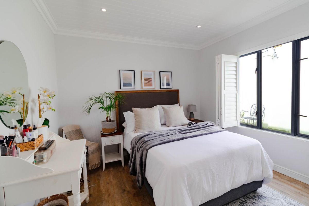 A well-maintained bedroom featuring timber-look flooring, recessed downlighting, and plantation shutters, offering a bright and comfortable living space.
