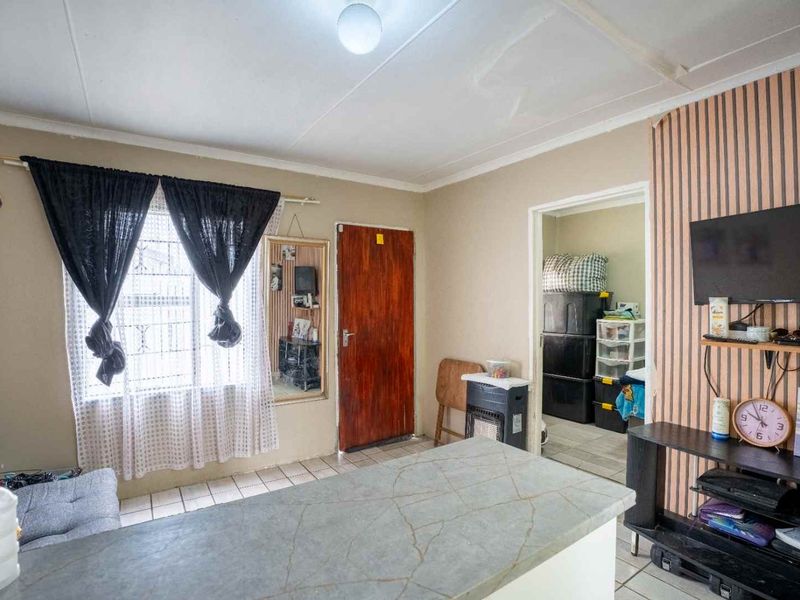 Open plan living area featuring tiled flooring, coved ceilings, and a central countertop, providing a functional space with potential for cosmetic updates.