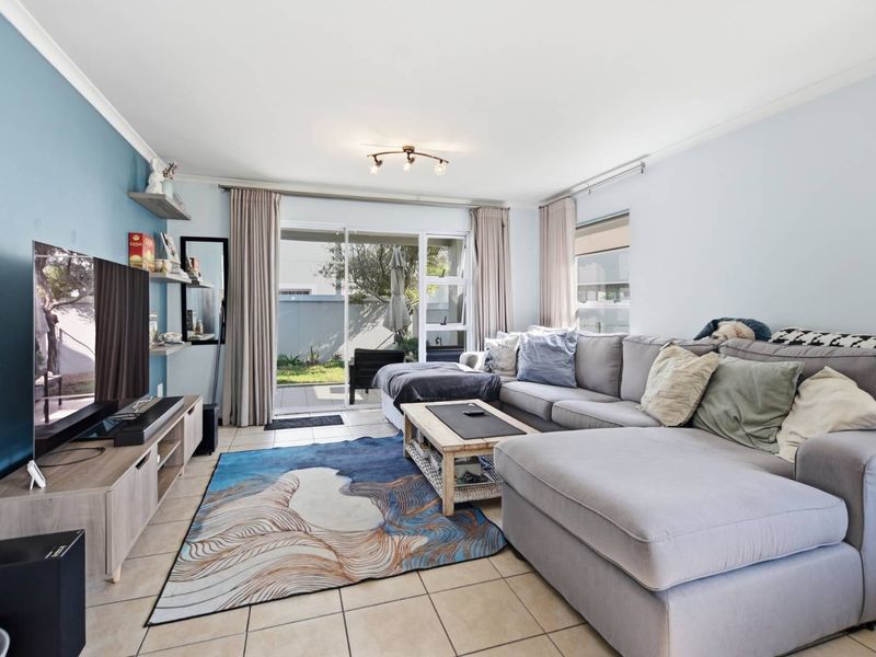 A bright and comfortable living room featuring tiled flooring, a feature wall, and large sliding glass doors providing access to the outdoor patio area.