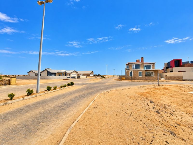 A view of the paved street and surrounding residential neighbourhood in a coastal estate setting.
