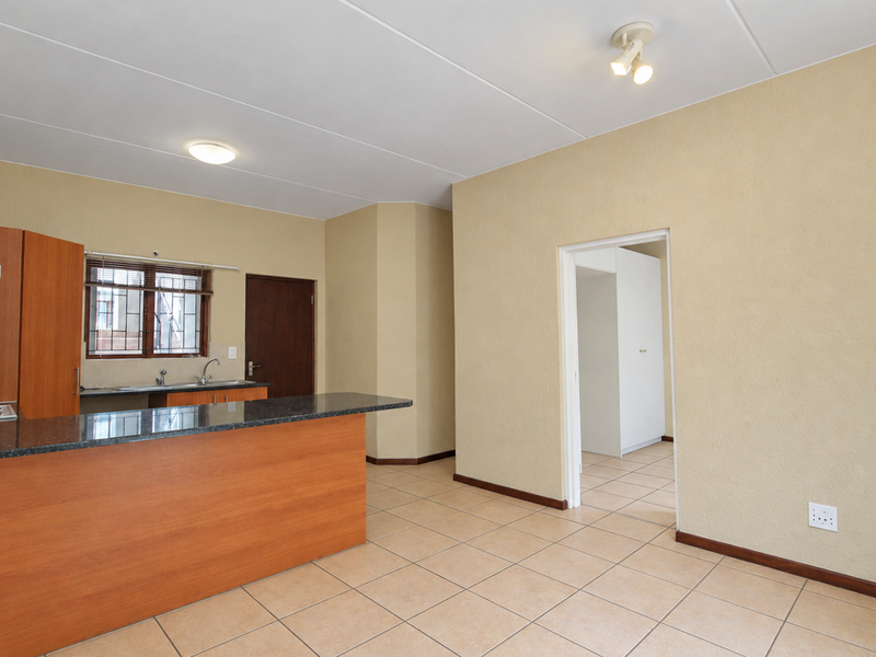 Open plan kitchen and living area featuring granite countertops, built-in cabinetry, and ceramic floor tiles, leading to an adjacent room.