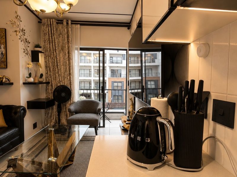 Modern open-plan living area featuring a compact kitchen with stone countertops, integrated lighting, and direct access to a private balcony.
