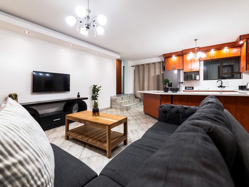 Spacious open-plan living area featuring a modern kitchen with wood cabinetry, stone countertops, and a central island, seamlessly flowing into the lounge space.