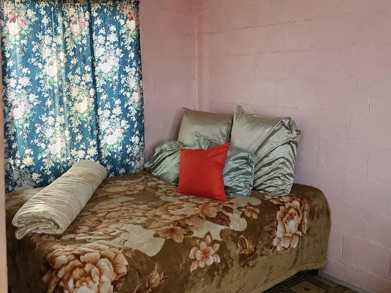 A bedroom featuring exposed concrete block walls and patterned vinyl flooring, offering a basic layout ready for cosmetic updates.