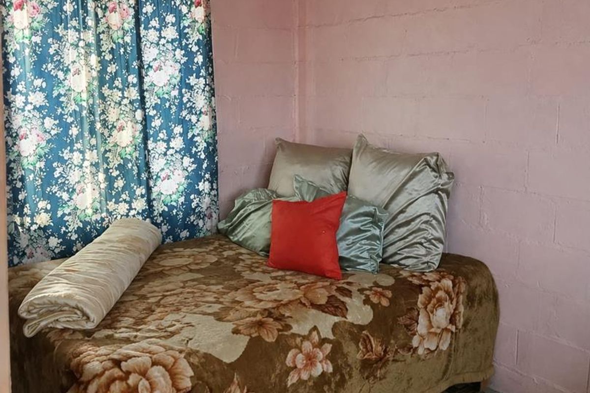 A bedroom featuring exposed concrete block walls and patterned vinyl flooring, offering a basic layout ready for cosmetic updates.