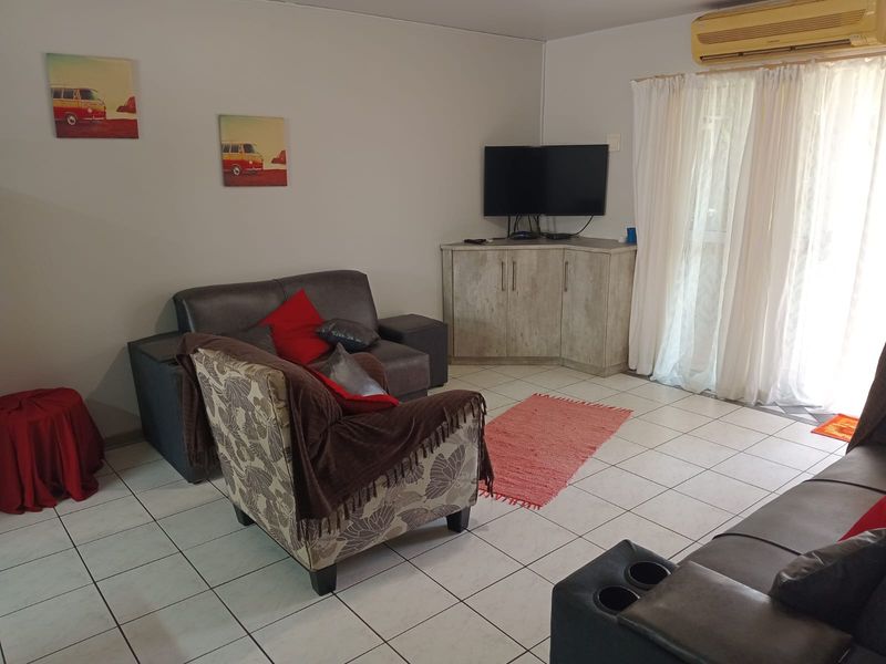A living room featuring tiled flooring, a wall-mounted air conditioning unit, and a sliding glass door providing access to the exterior.