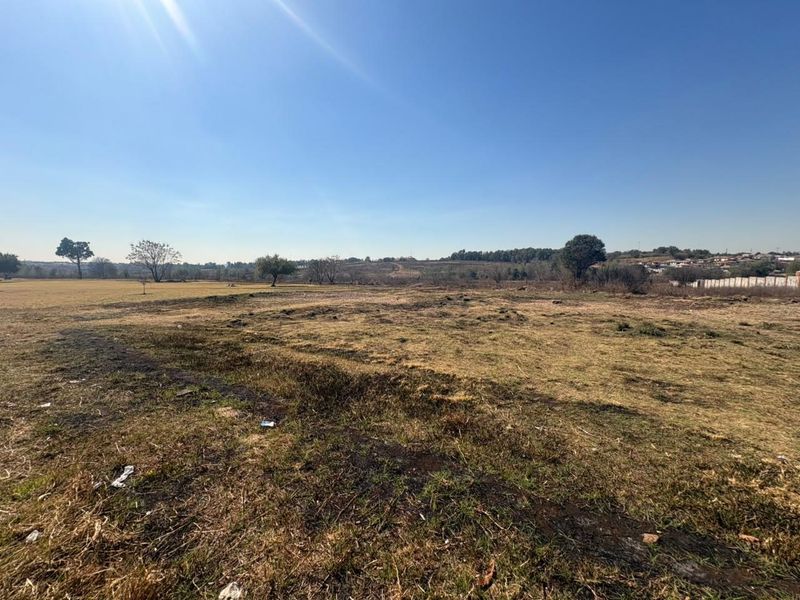 A wide-angle view of a vacant residential plot featuring open grassland and natural landscape.