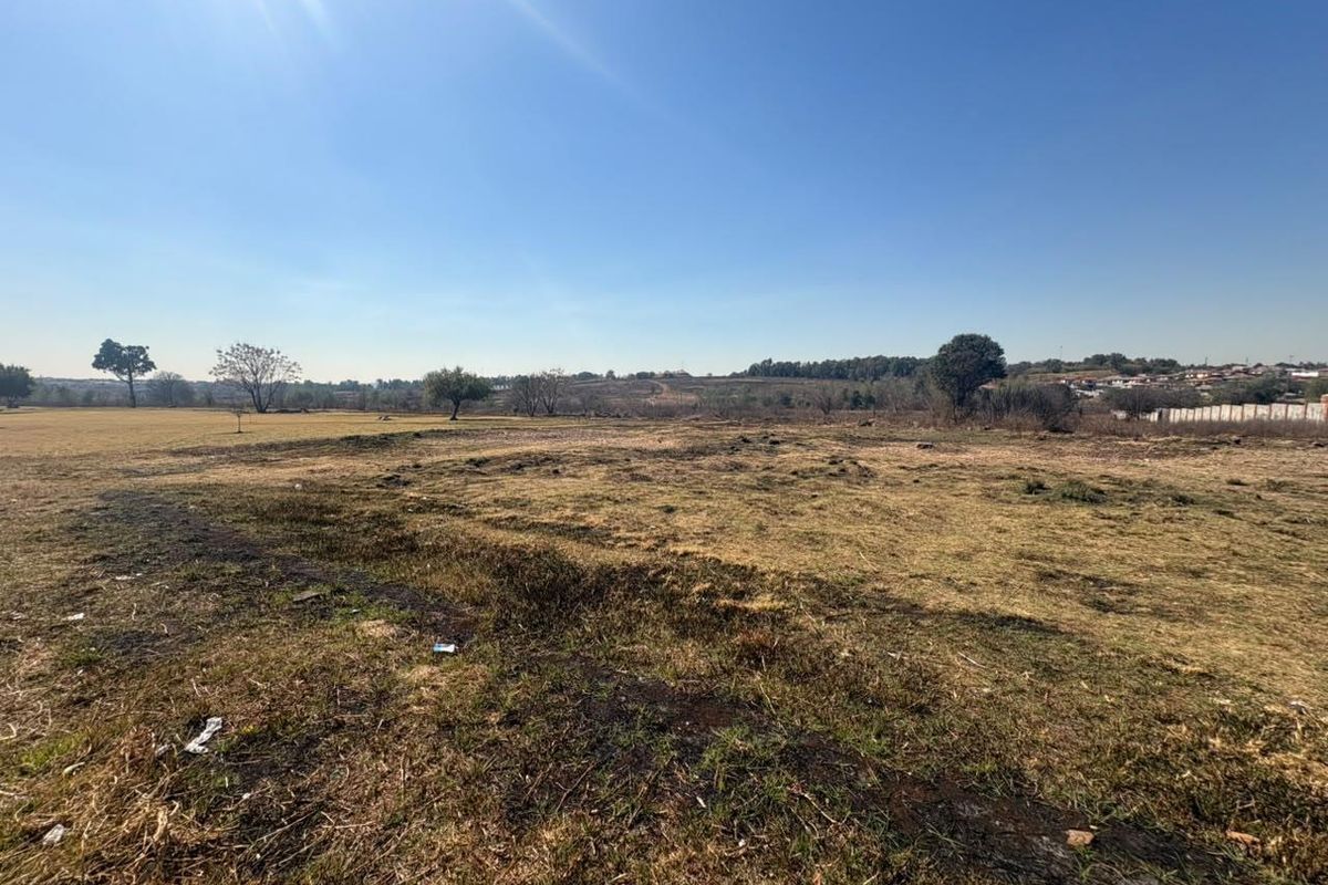 A wide-angle view of a vacant residential plot featuring open grassland and natural landscape.