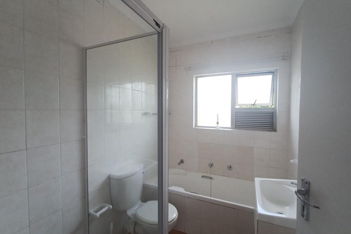 A functional bathroom featuring a built-in bathtub, a separate glass-enclosed shower, and a standard vanity basin with tiled wall finishes.