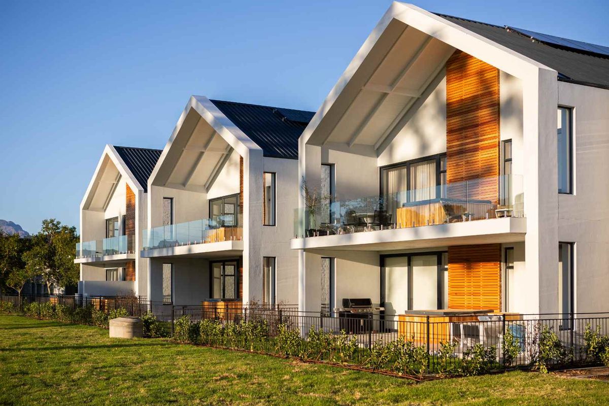 Modern apartment complex featuring contemporary pitched roof architecture, timber accents, glass balconies, and well-maintained landscaped grounds.