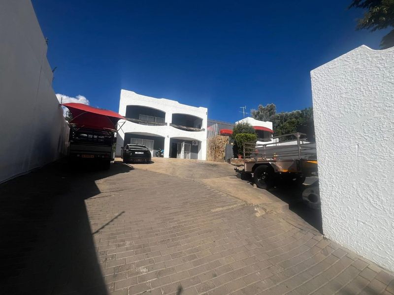 Front exterior view of a two-story residential property featuring a paved driveway and boundary walls.