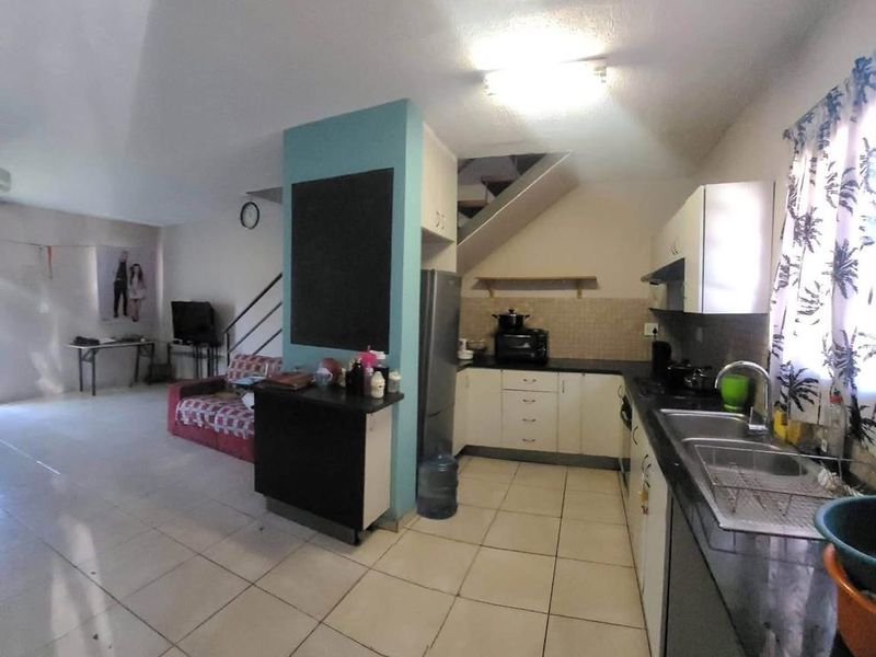 Open plan living and kitchen area featuring tiled flooring, built-in cabinetry, and a staircase leading to the upper level.
