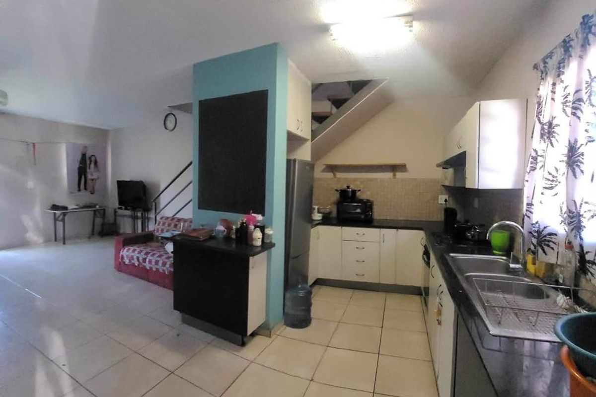 Open plan living and kitchen area featuring tiled flooring, built-in cabinetry, and a staircase leading to the upper level.