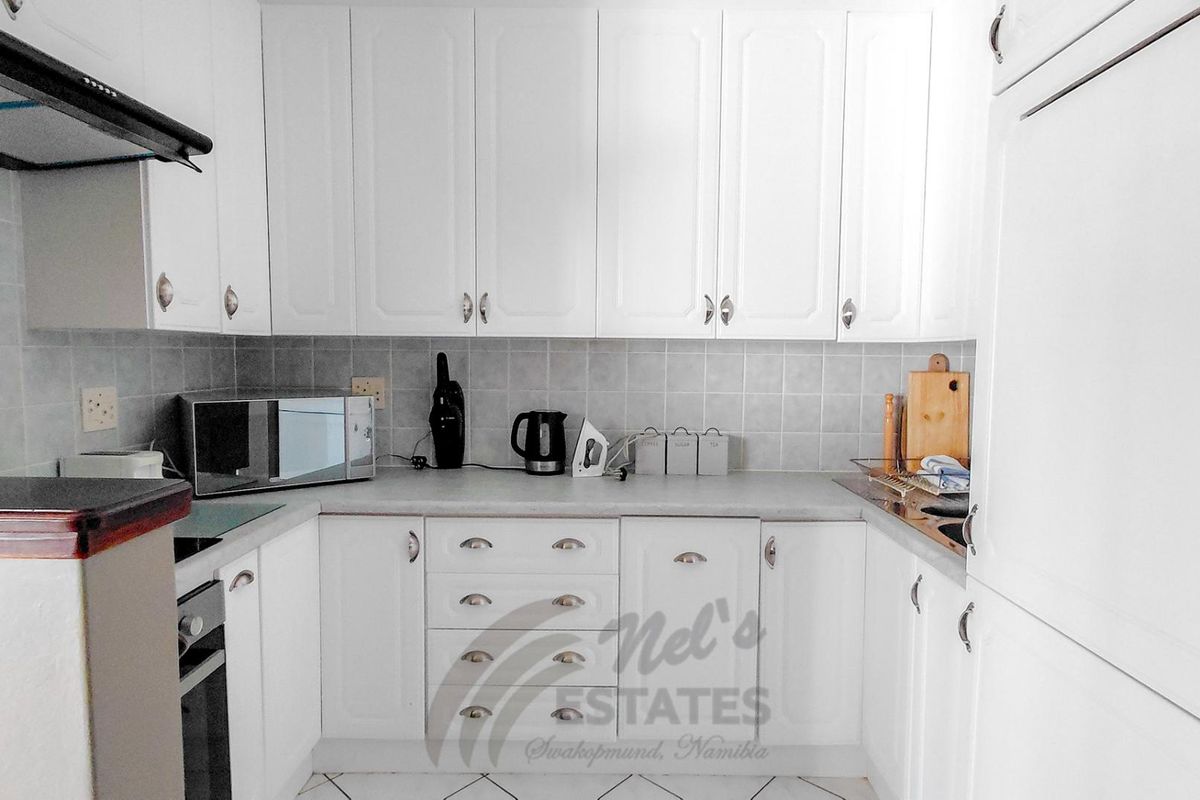 A functional kitchen featuring white cabinetry, tiled backsplash, built-in oven, and extractor fan with ample counter space.