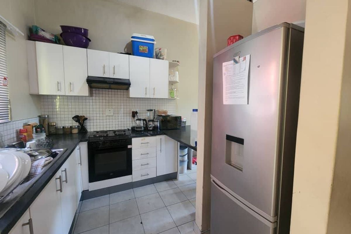 A functional kitchen featuring white cabinetry, a built-in oven with extractor fan, dark countertops, and tiled flooring.