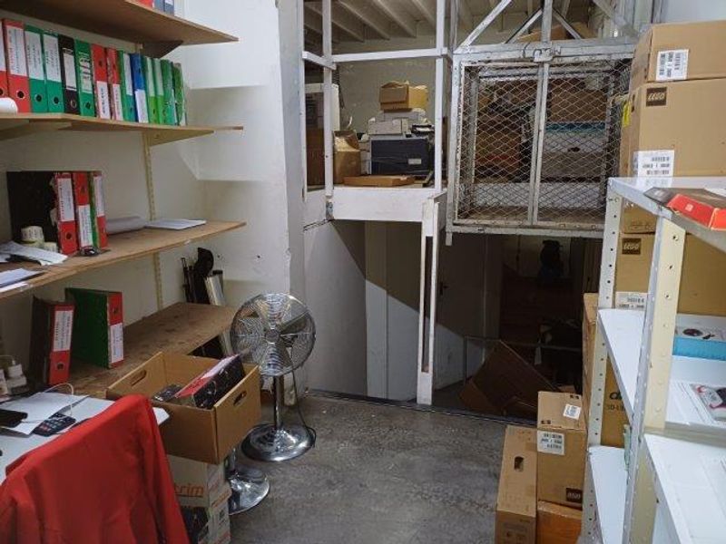 Utility storage area featuring built-in shelving units and a freight lift, suitable for industrial or office storage purposes.