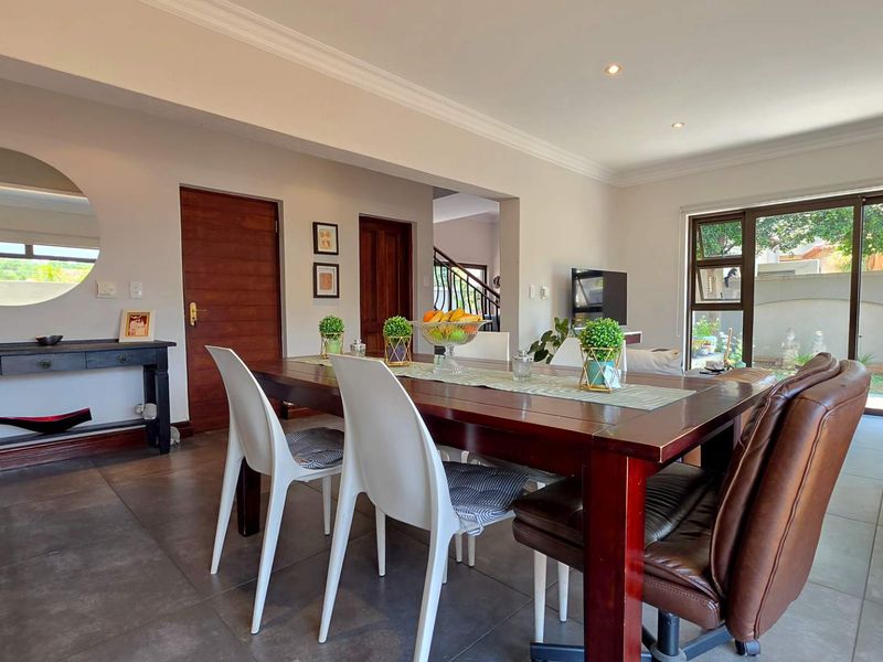 Spacious open-plan dining and living area featuring tiled floors, recessed lighting, and large sliding glass doors providing access to the outdoor space.