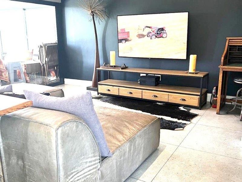 A modern living room featuring large format floor tiles, a dark accent wall, and a wall-mounted split-system air conditioning unit.