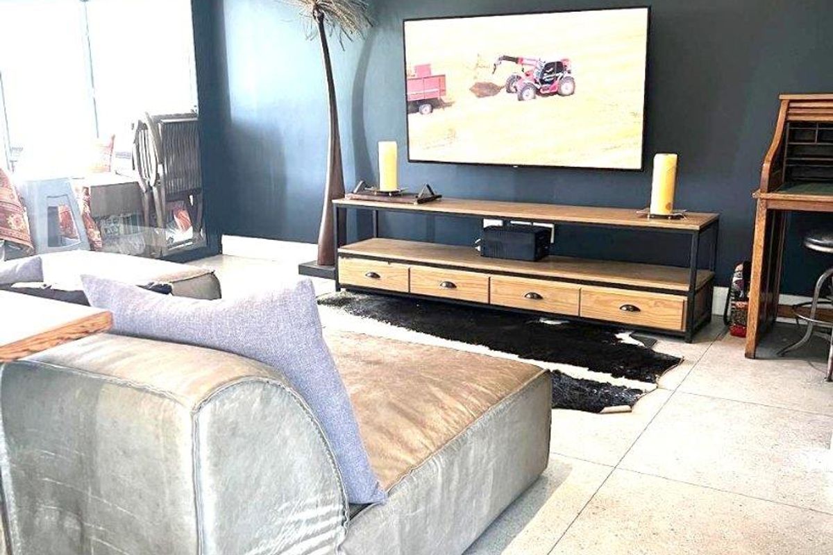 A modern living room featuring large format floor tiles, a dark accent wall, and a wall-mounted split-system air conditioning unit.