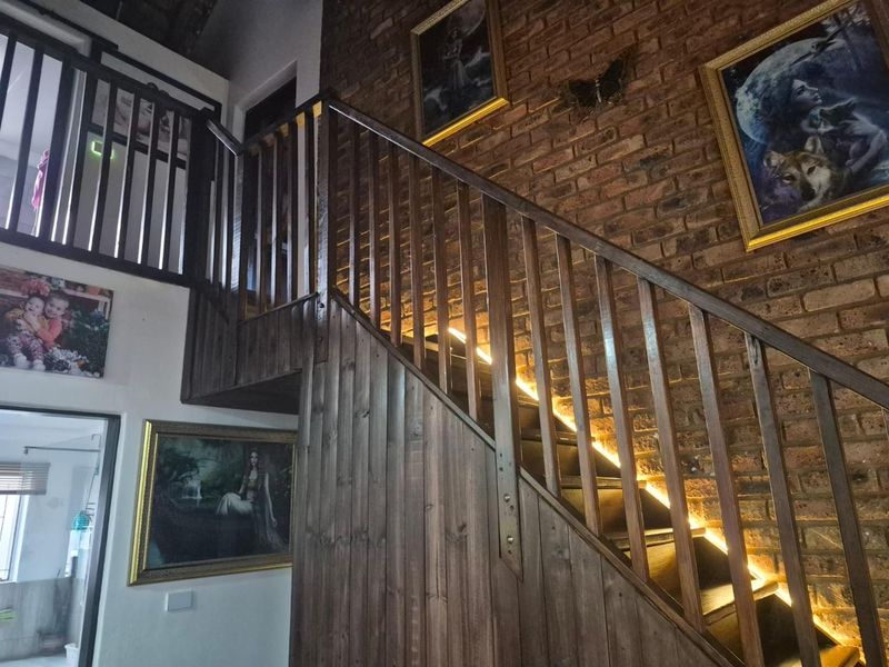 A characterful hallway featuring a timber staircase with integrated LED lighting and an exposed brick feature wall.