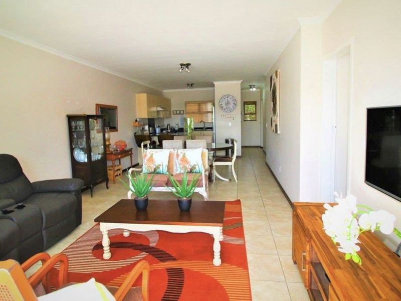 Open-plan living and dining area featuring tiled flooring and a functional kitchen with breakfast bar, offering a versatile layout for modern apartment living.