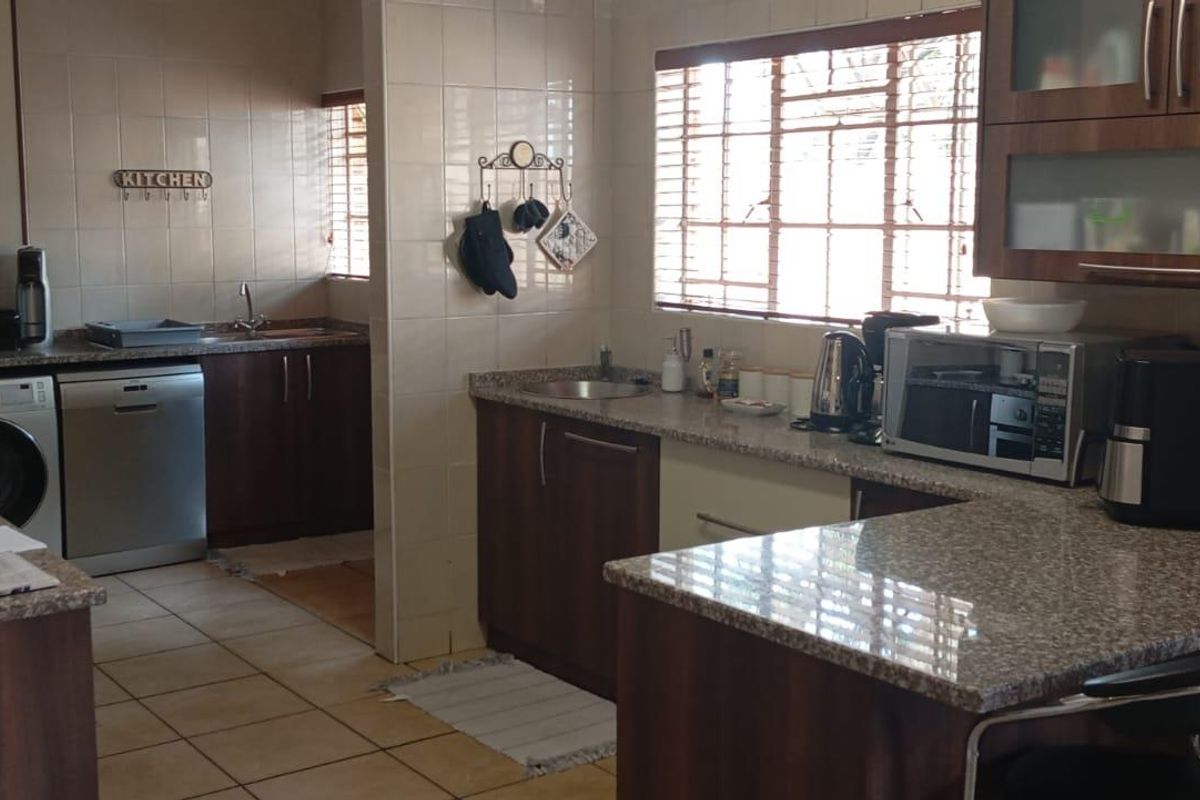 A functional kitchen featuring dark wood cabinetry, granite countertops, tiled flooring, and a breakfast bar area with integrated appliance spaces.