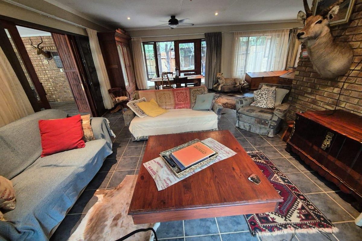 Spacious living area featuring tiled flooring, a brick fireplace, and large windows providing natural light and access to the outdoor space.